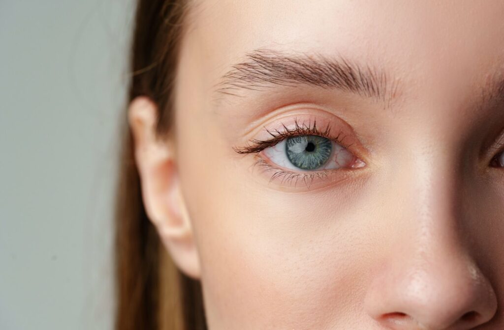Close-up of a person’s blue-green eye with visible lashes and natural skin texture around the eyelid and brow area.